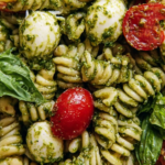 Pesto pasta salad with basil pesto, cherry tomatoes, mozzarella, and fresh herbs